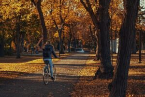 Woman riding a bike surrounded by trees.