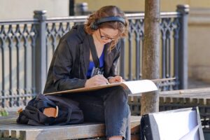 Woman with earphones sitting on a bench.