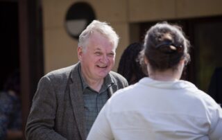 Induction day 2025 A man with grey hair chatting to a woman. Her back is to the camera.