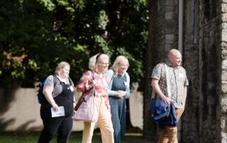 Students walking induction day 2025 Four people walking and smiling. They are walking outside.