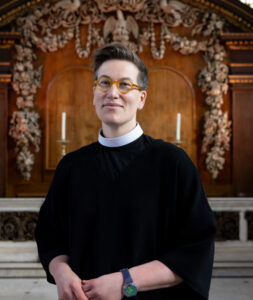 Ayla Lepine, Associate Tutor from St Augustine's College. She is standing in a church smiling.