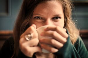 A woman with happy eyes holding a mug of drink.