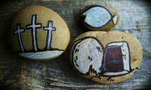 Three painted stones showing Christian Biblical images - crosses, bread and fish