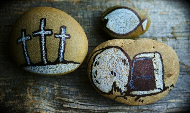 Three painted stones showing Christian Biblical images - crosses, bread and fish